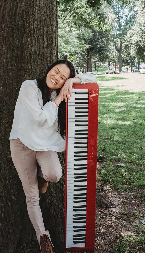 Tessa Ying smiling beside a red keyboard in a park